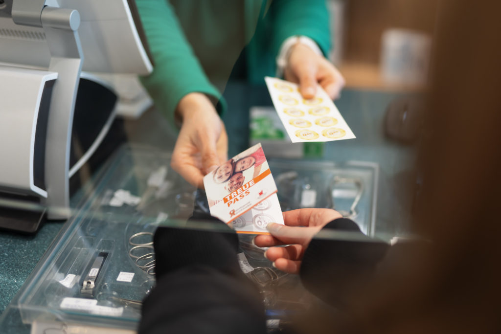 Eine Person übergibt einen Gutschein an einen Apotheker an der Kasse. In der Germania Apotheke in Erfurt