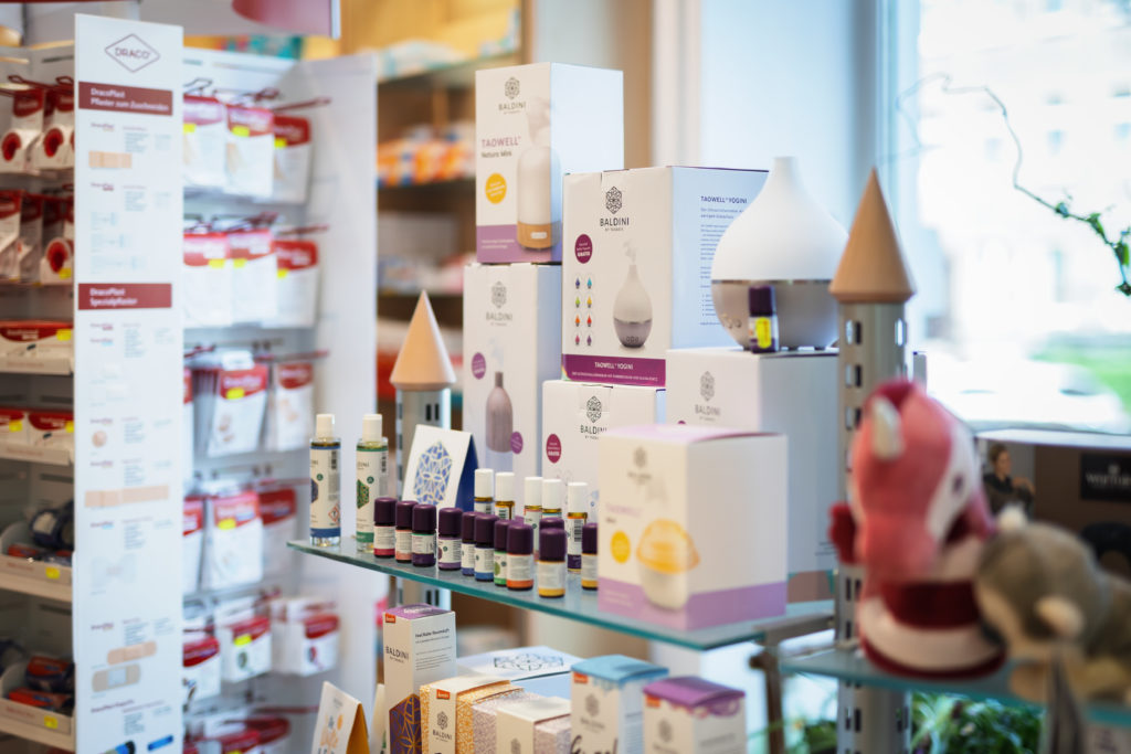 Regal mit verschiedenen Aromatherapie-Produkten, einschließlich Diffusoren und ätherischen Ölen in einer Apotheke. In der Germania Apotheke in Erfurt