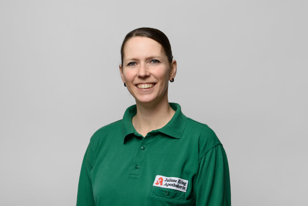 Porträt von Frau Kring in grüner Polo-Uniform mit einem Apothekenlogo auf der Brust. In der Germania Apotheke in Erfurt