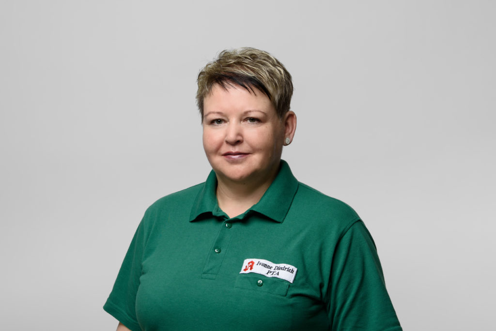 Frau Diedrich mit kurzem, blondem Haar in grüner Polo-Uniform mit Namensschild. In der Germania Apotheke in Erfurt