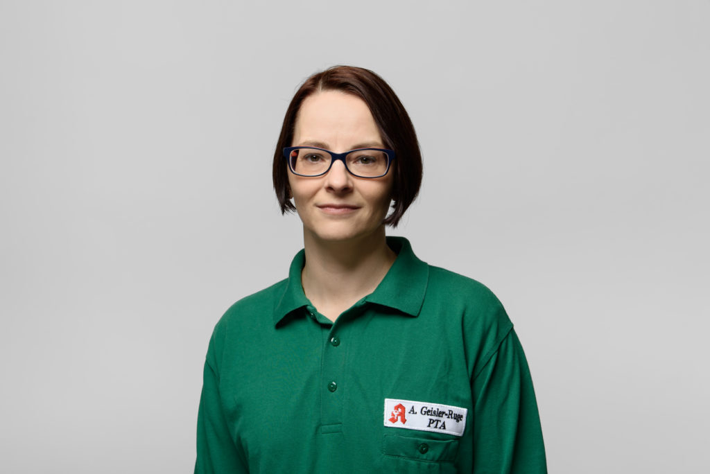 Frau Geisler-Ruge mit kurzen braunen Haaren und Brille, trägt ein grünes Polo-Shirt mit Namensschild. In der Germania Apotheke in Erfurt
