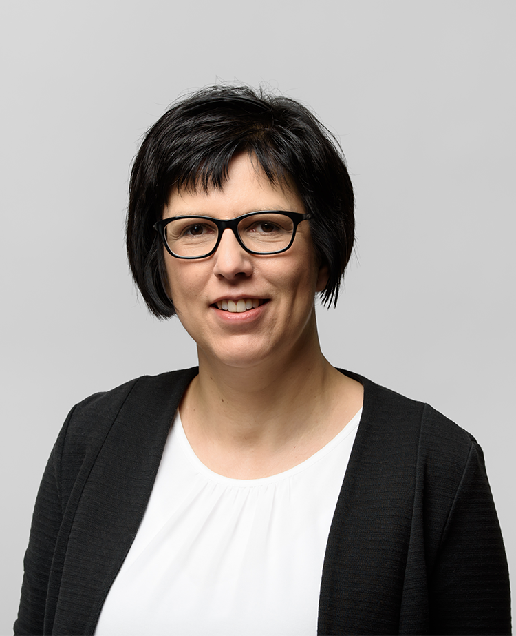 Frau mit kurzen, dunklen Haaren und Brille, die in die Kamera lächelt. In der Germania Apotheke in Erfurt